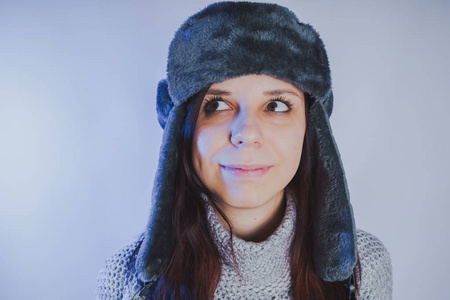 一个女孩在一个摄影棚里用蓝色滤镜风格的服装帽子和毛衣拍摄的情感肖像。