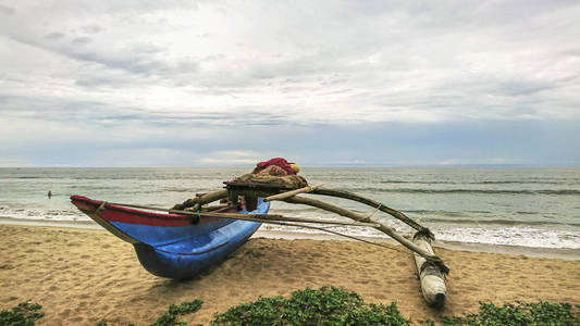 传统的蓝色渔船在斯里兰卡空旷平静的海滩上。