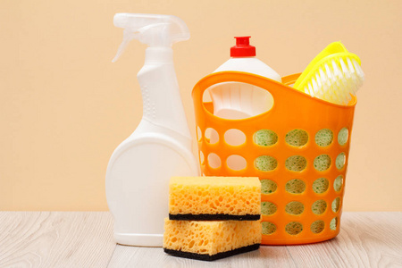 塑料瓶的洗碗液，玻璃和瓷砖清洁剂，用于微波炉和炉子篮子刷海绵的米色背景。 洗涤和清洁的概念。