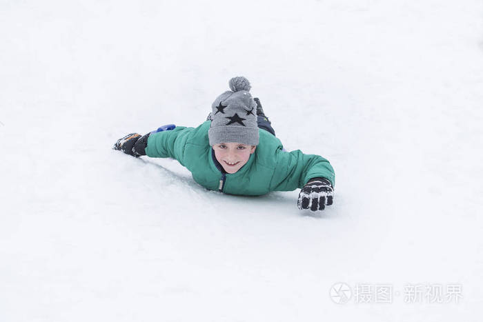 笑的男孩从山上骑在肚子上季节性概念冬天
