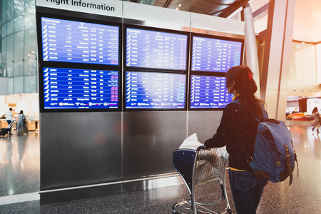 女乘客在机场查看航班信息板