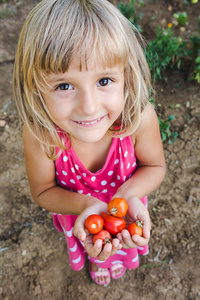可爱的卷发女孩手里拿着樱桃番茄