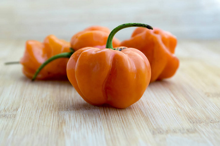 在木竹桌上的辣椒中国辣椒哈伯诺橙，成熟的非常热的水果