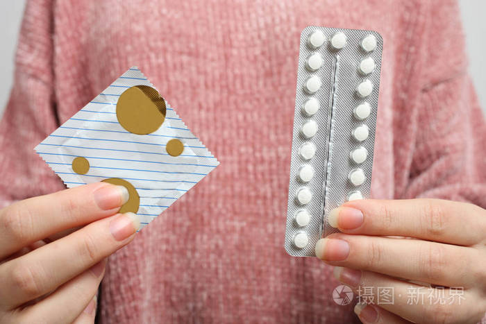 妇女手拿口服避孕药和避孕套的选择概念妇科性教育