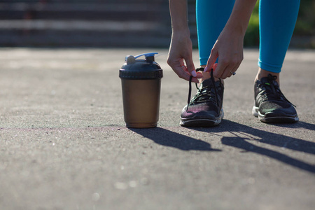 年轻健康的女人在慢跑时在体育场系鞋带。 文本空间