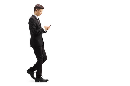 一个穿着黑色西装的年轻人在白色背景白色背景下被隔离在一部手机上的长轮廓照片