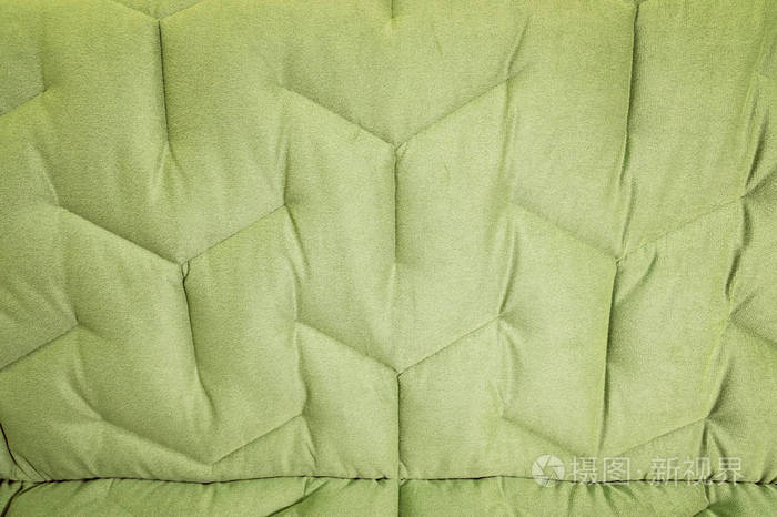 特写舒适的绿色柔软的沙发与卷曲的缝合。现代设计