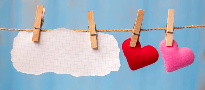 红色心形装饰挂在线上，蓝色木制背景上的文字复制空间。 爱情婚礼浪漫快乐情人节假期概念