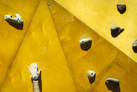 s hands attached to the supports of an outdoor climbing wall.