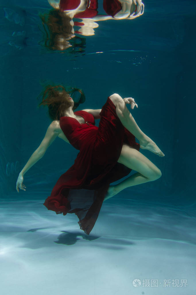 美丽的自由的自由潜水员一个人穿着红色的长裙独自在深水中游泳