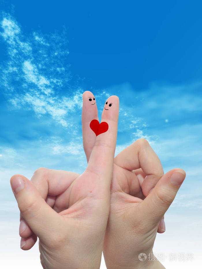 在多云的蓝天背景下女性双手用两根手指涂有红色的心