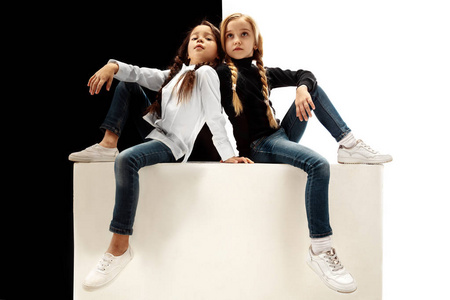 两个悲伤的Seriouus女孩在白色和黑色工作室背景上的肖像。 人类情感的概念。 比较。 童年微笑快乐孩子友谊的概念
