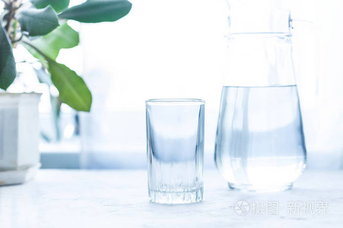 白色桌子上的水杯和带水的玻璃瓶复制空间