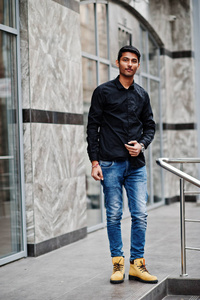 时尚的印度模特男子穿休闲服装，黑色衬衫在印度街头摆在户外。