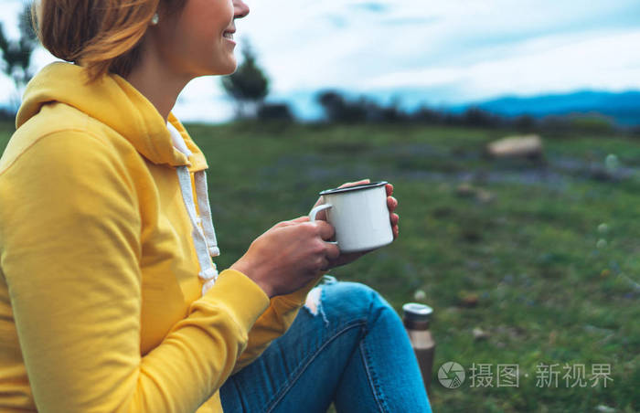 在户外自然公园的草地上,幸福的女孩手捧着一杯热茶,美丽的女人,时髦
