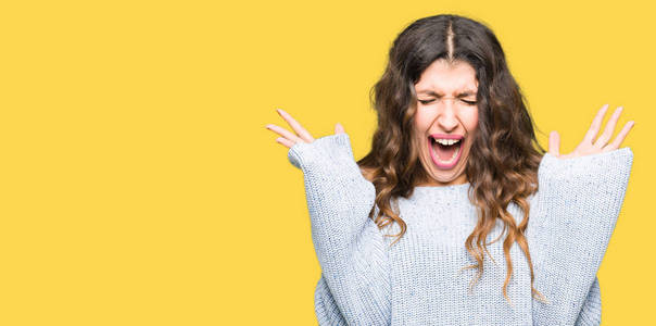 穿着冬天的毛衣庆祝疯狂和疯狂的成功,举起手臂和闭上眼睛尖叫兴奋