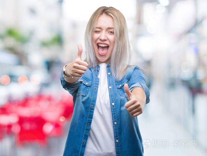 年轻的金发女人在孤立的背景下赞成做积极的手势用手竖起大拇指微笑并