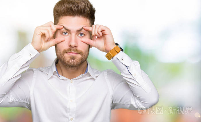 年轻英俊的商人试图用手指睁开眼睛,困倦而疲惫,因为早晨的疲劳