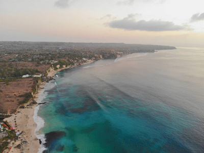 蓝天的鸟瞰,沙质海岸线上有岩石悬崖.