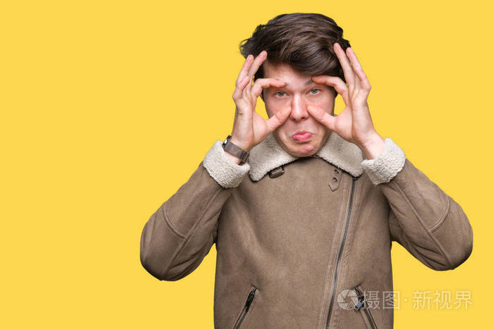 年轻的帅哥穿着冬天的外套在孤立的背景下试图睁开眼睛手指困倦疲倦