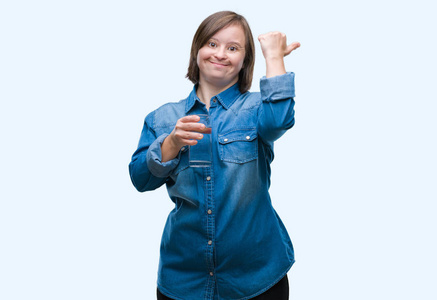 年轻的成年妇女患有唐氏综合症，在孤立的背景下喝水，用拇指指向一边，脸上洋溢着幸福的笑容