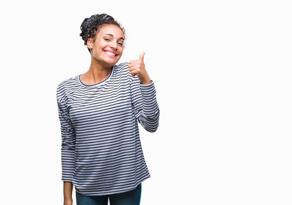 年轻的辫子非裔美国女孩穿着毛衣，在孤立的背景下，用手做快乐的竖起大拇指的手势。 赞许的表情看着相机，显示出成功。