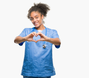 年轻的非洲美国医生女人在孤立的背景下微笑，在爱中显示心脏的象征和形状与手。 浪漫的概念。