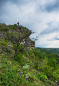 峡谷上方悬崖上的游客。 在风景如画的河流上方的悬崖上的人。 春天的黎明