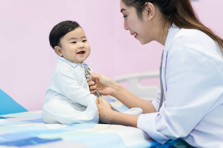 亚洲医生女人在医院用听诊器检查一个小男孩。 医学和保健概念