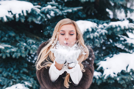 圣诞女孩户外肖像。 冬天的女人在公园里吹雪