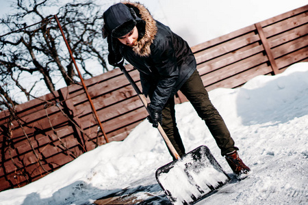 年轻人在后院或车道上用雪铲和清洁雪的肖像。