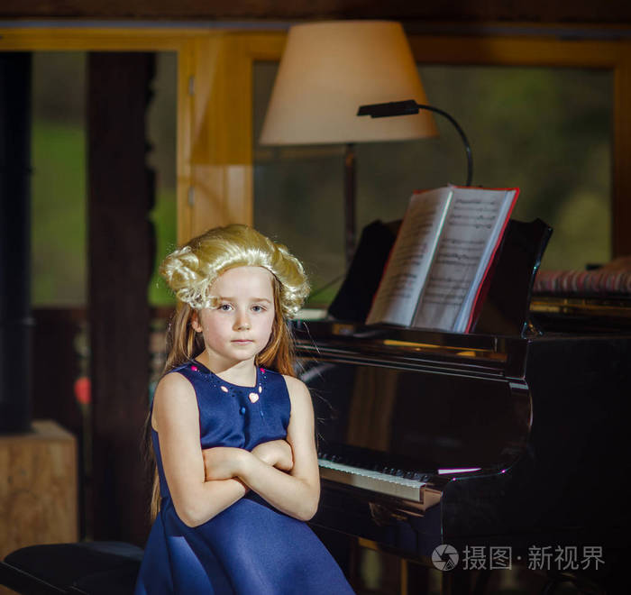可爱的小女孩弹钢琴,穿着复古摩扎特维格室内