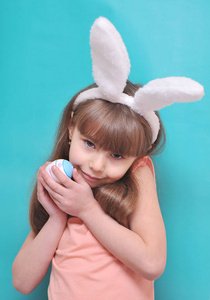 可爱的小女孩带着兔子耳朵拿着鸡蛋。 复活节快乐。