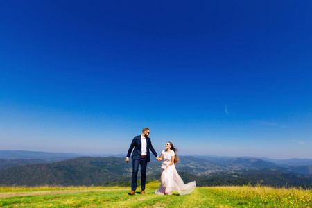 在美丽的风景背景下,新婚夫妇手牵手互相看着对方的真诚情感照片