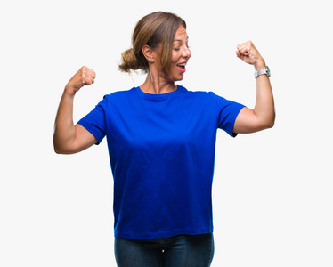 中年老年西班牙裔妇女在孤立的背景下表现出手臂肌肉微笑自豪。 健身理念。