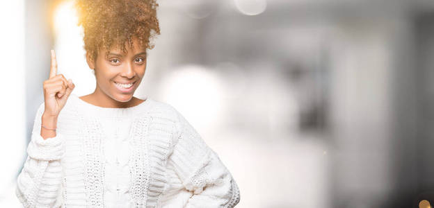 美丽的年轻非洲裔美国妇女穿着冬天的毛衣，在孤立的背景上指点着成功的想法。离开而快乐。一号。