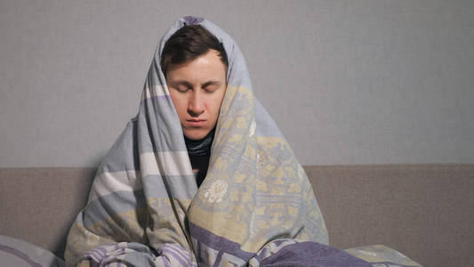 不快乐的年轻人包裹在温暖的毯子里
