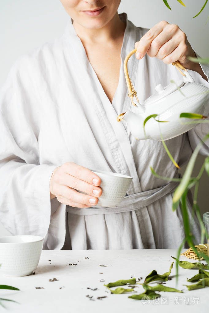 在茶道上从茶壶到茶杯倒茶的女人