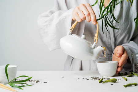 女性手从茶壶倒茶到茶杯选择性聚焦。 冲泡和喝茶。