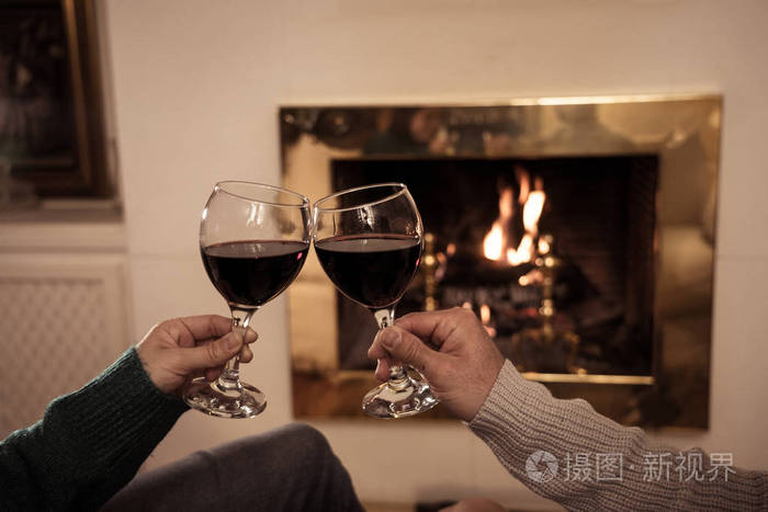 亲密的浪漫夫妇举着两个红酒杯在火中品尝在寒假假期圣诞节或周年纪念