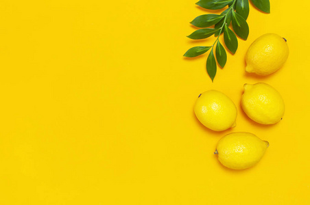 成熟多汁的柠檬和鲜黄色背景上的绿叶。 柠檬水果柑橘最小概念维生素C。创意夏季食品极简主义背景。 平躺顶视复印空间