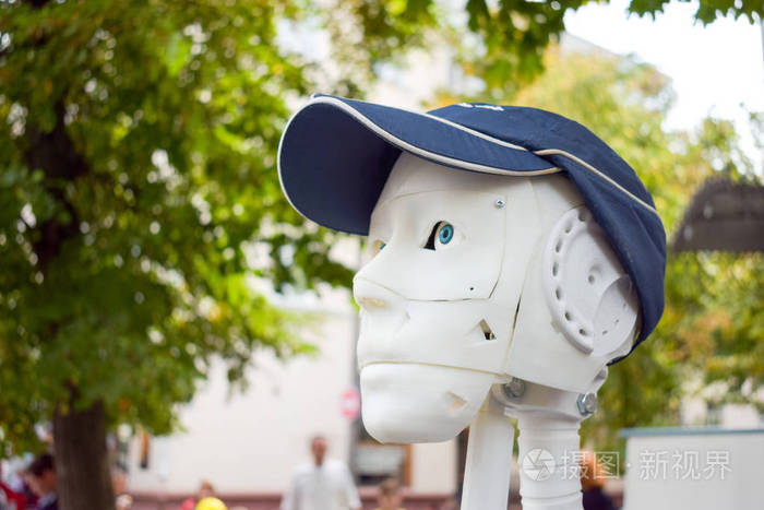 未来派男子，白色机器人打印在3D打印机上。戴着棒球帽的塞博格头。3D打印，三维物体