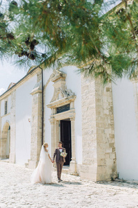 在塞浦路斯的城市街道上举行婚礼。 美丽的一对夫妇在城市的建筑上走来走去，谈笑风生。