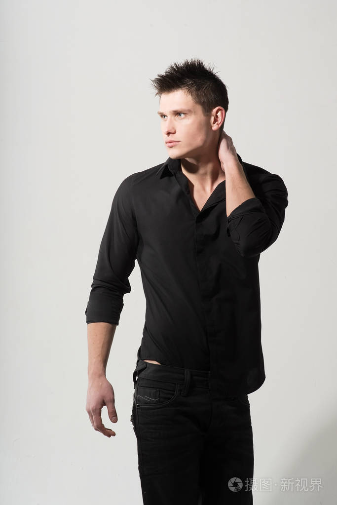 年轻白种人的肖像穿着黑色衬衫摆在白色背景上