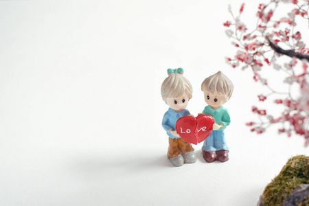 两个数字，男孩和女孩，一半的红色的心在手中。 恋爱中的幸福夫妇。 恋爱关系恋爱观念