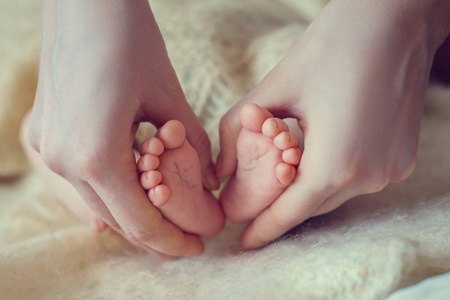 宝宝的脚在妈妈手里。妈妈和她的孩子。幸福的家庭观念。美丽的产妇概念形象..