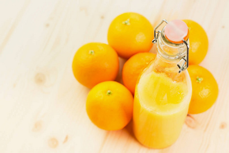 一瓶新榨的橙汁，在木制背景上加橘子。健康的生活方式观念。从上面看。文本的复制空间。