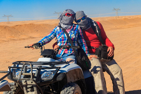 年轻夫妇在狩猎旅行通过埃及沙漠驾驶ATV。 埃及赫赫达附近沙漠中的四轮自行车狩猎