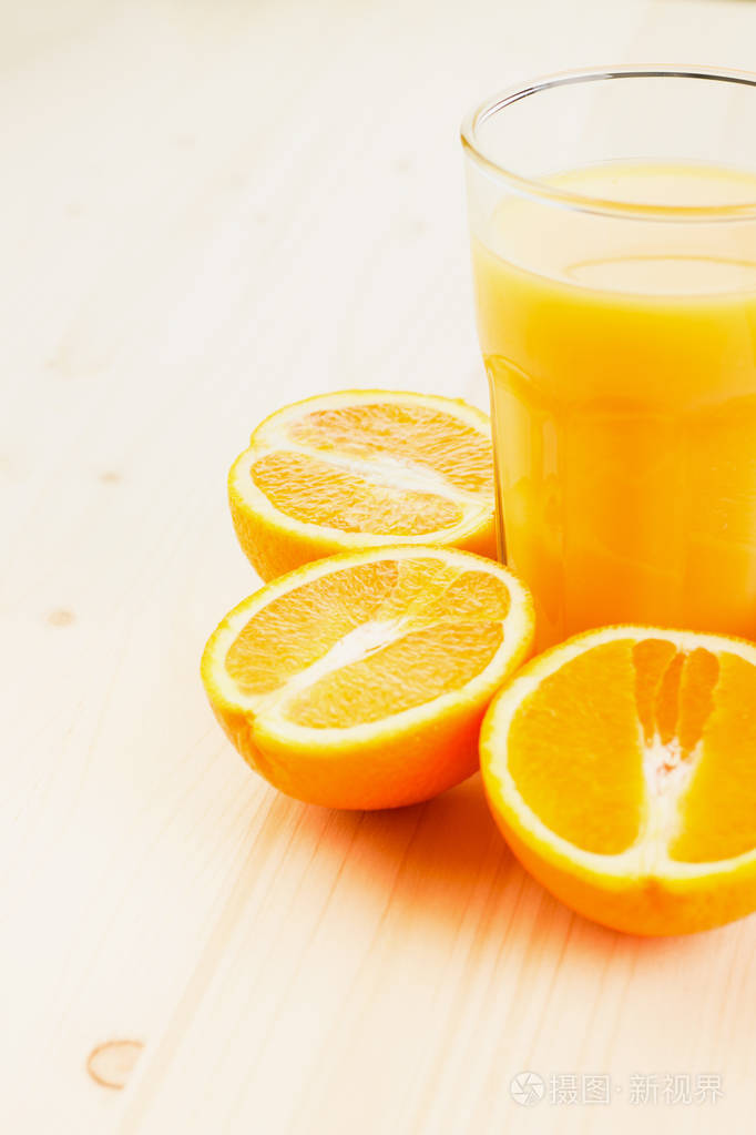 一杯新榨的橙汁在木制背景上切成橙色的半片健康的生活方式概念复制