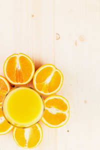 一杯新榨的橙汁，在木制背景上切成橙色的半片。 健康的生活方式概念。 复制文本空间。 从上面看。